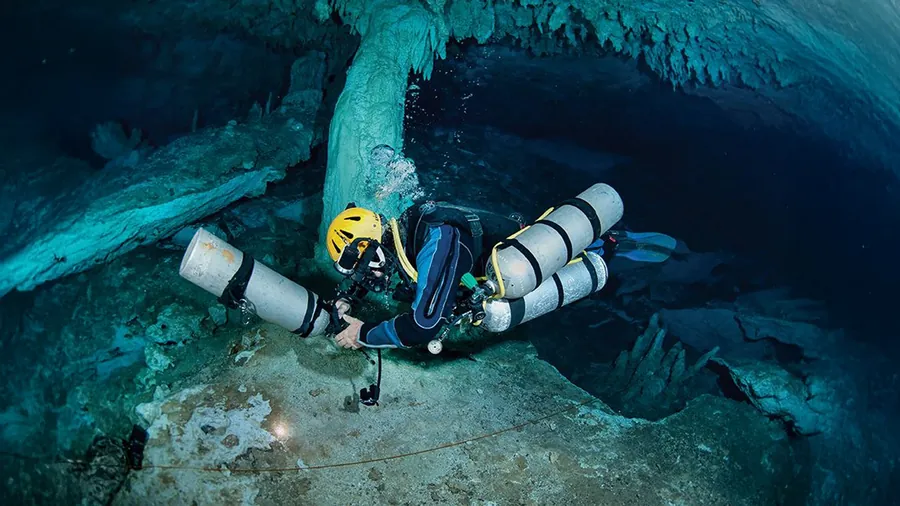 Diver at the entrance of a cavern in natural light