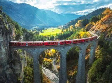 Tren rojo del Bernina Express sobre un viaducto de piedra en los Alpes